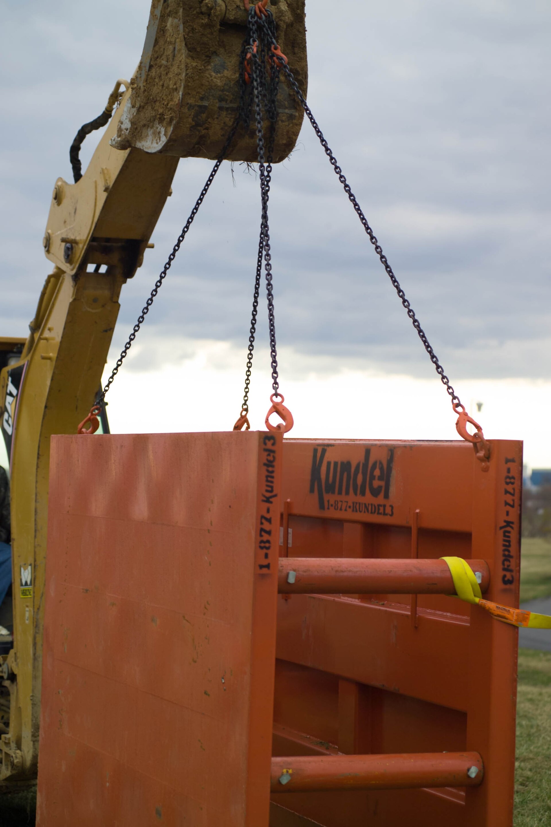 Ein Bagger lässt eine stählerne Verbaubox in einen offenen Graben hinab